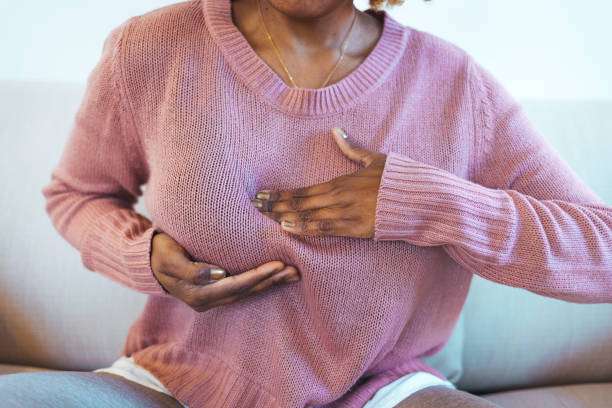 Woman in pink checking her breasts, considering a breast pump for comfort.