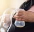Woman holding breast pump bottle with milk, close-up.