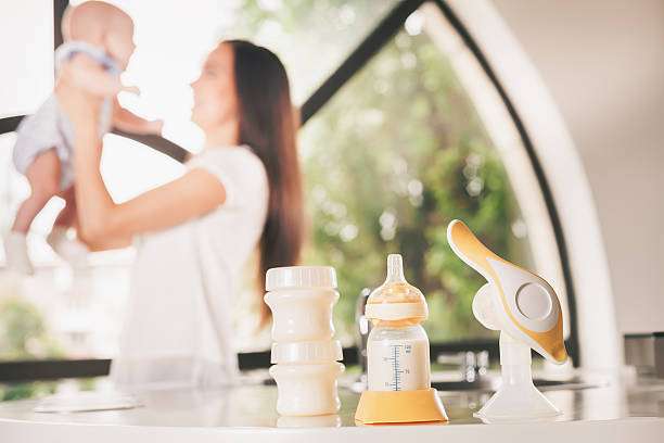 Woman with baby and breast pump supplies on counter.