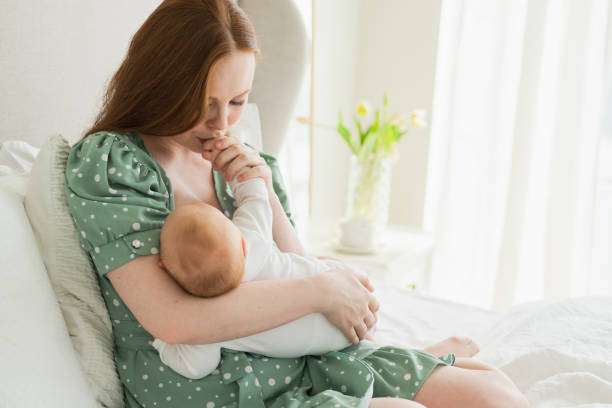 Mother breastfeeding baby on bed, floral dress