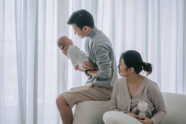 Family with baby and breast pump bottle nearby.
