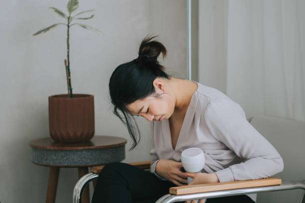 Tired new mom sits, using a discreet wearable breast pump at home.