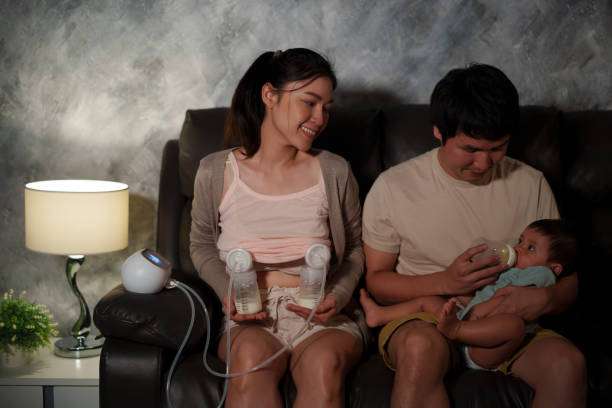 Couple using breast pump while caring for baby.