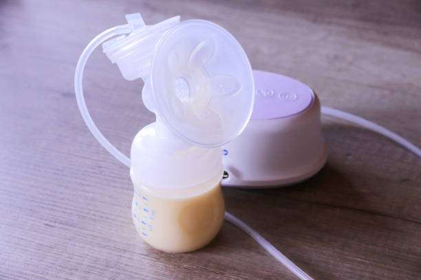 Electric breast pump with a bottle of expressed milk on a wooden table.